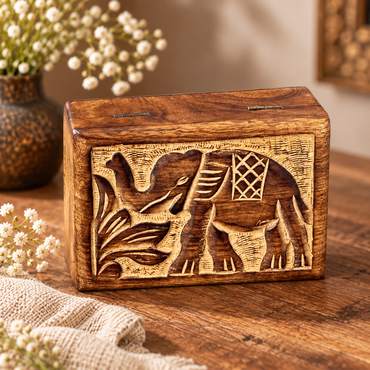Hand-carved elephant wooden box on a warm wood tabletop with linen