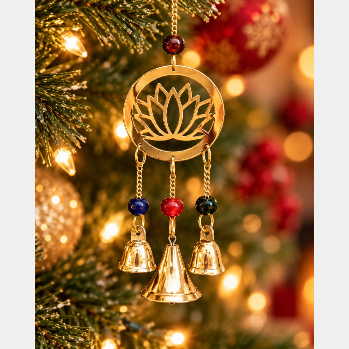 Close-up of a brass lotus chime with colorful beads and three bells against a lit Christmas tree