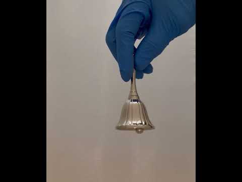 Video of a 3.5-inch tall nickel polished brass hand bell being rung, showcasing its clear and resonant sound. The bell has a polished finish and a classic design, ideal for decorative or functional use.